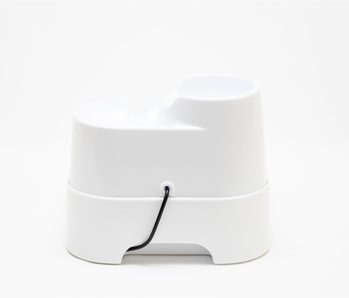 A view which shows the rear of the white pet drinking fountain for cats and dogs which shows where the electric cord is attached to the fountain.