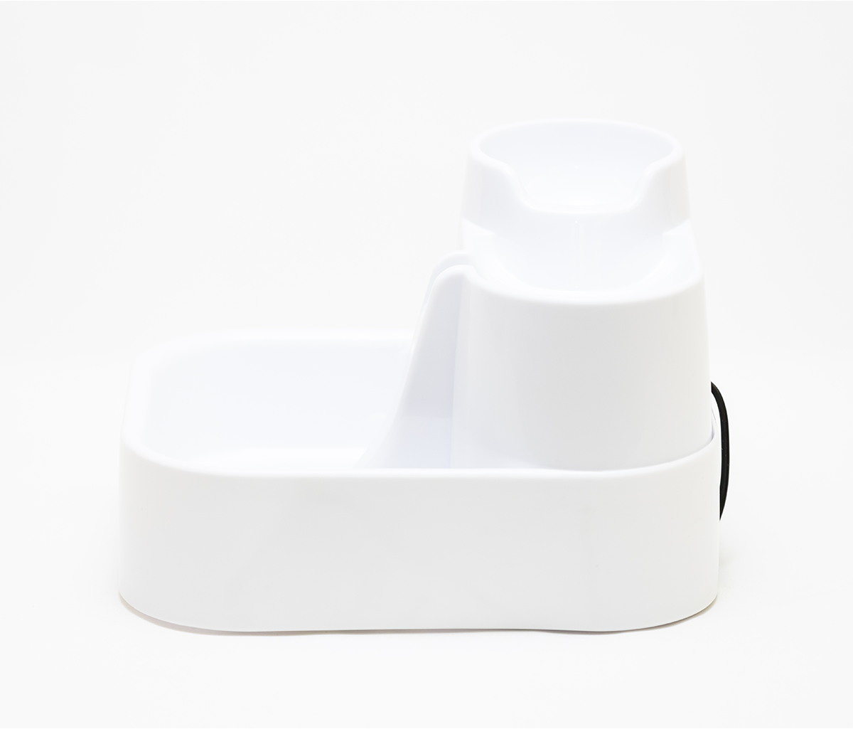 A side view of the pet drinking fountain that comprises of three different levels in the colour white against a background that is also white.