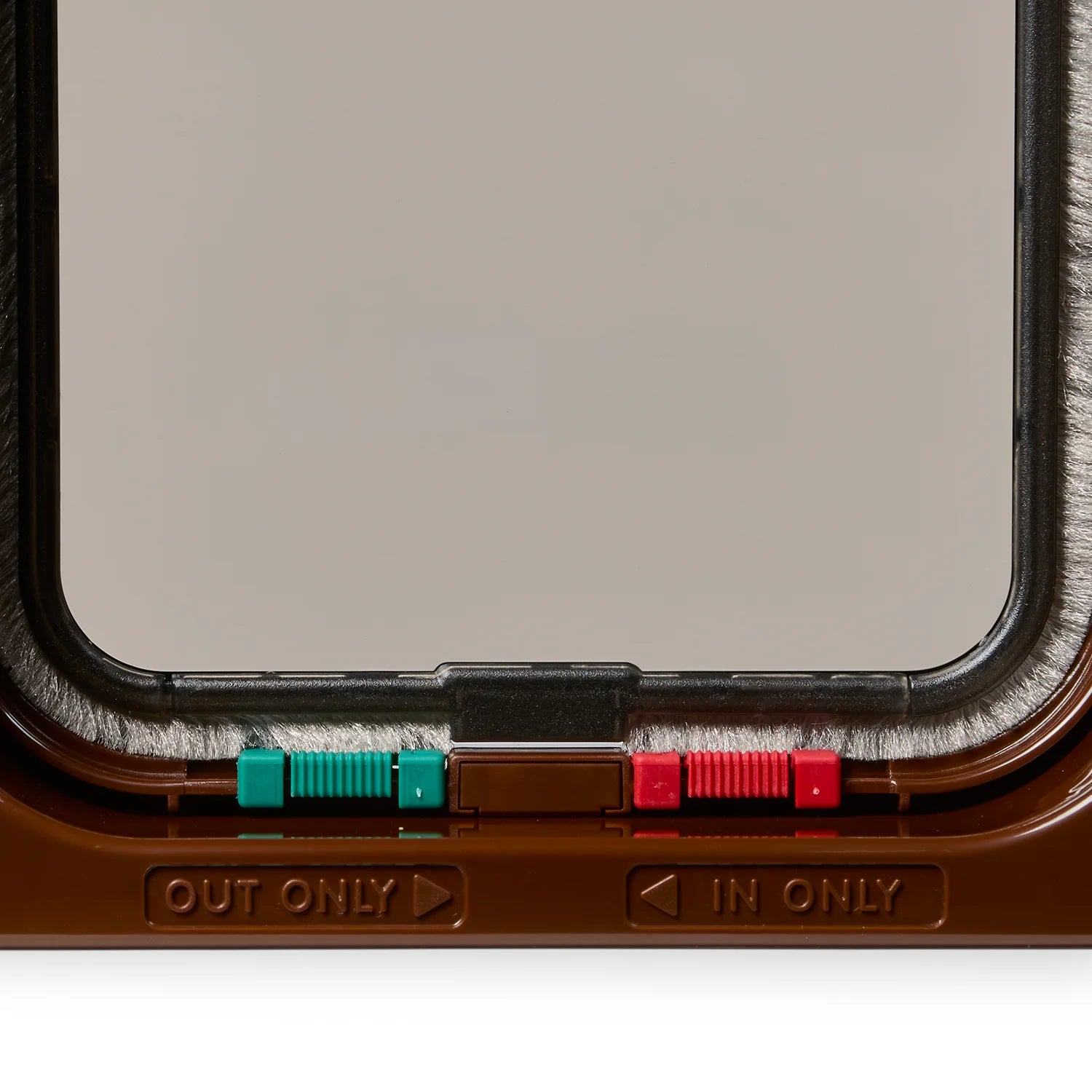 Close-up of a lockable cat flap in brown  with 'IN ONLY' and 'OUT ONLY' labels below the red and green locks on the frame. 