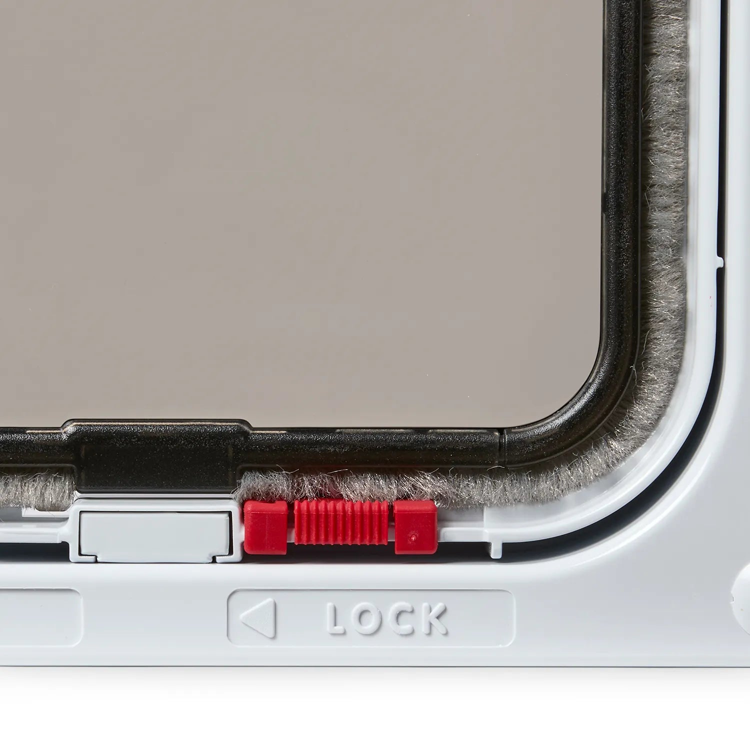 Close-up view on one of the locking mechanisms on the white pet door for average size cats.  